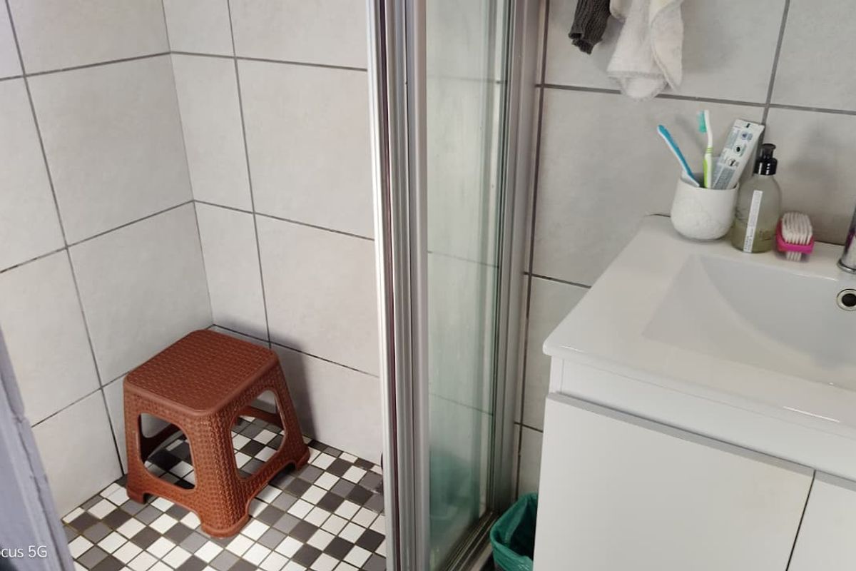 A functional bathroom featuring a shower enclosure with tiled walls and a modern vanity basin with a mixer tap.