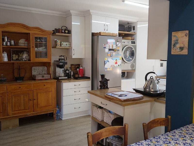 A functional kitchen area featuring white cabinetry, a central island, and integrated laundry appliances, providing a practical layout for daily use.