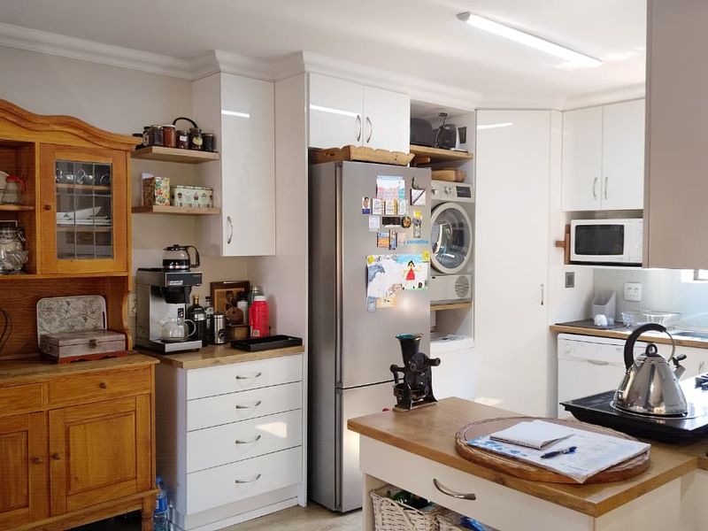 A functional kitchen featuring white cabinetry, wooden countertops, integrated laundry appliances, and a built-in microwave, offering a practical layout for daily use.