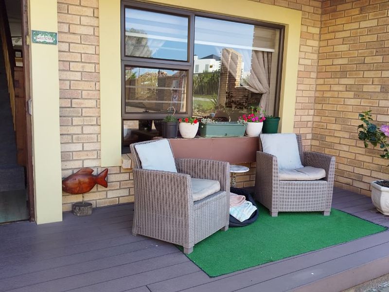 A covered patio area featuring composite decking and a brick facade with a large window.