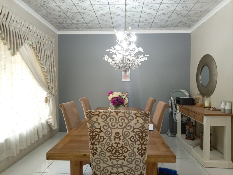 A dining room featuring tiled flooring, a decorative ceiling, and a central pendant light fixture, creating a defined space for meals.