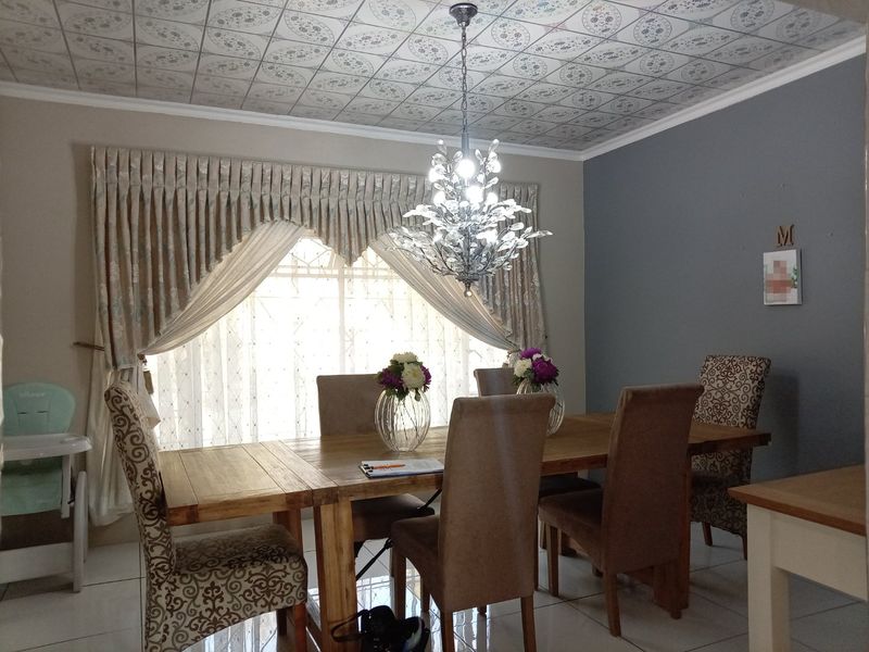 Dining room featuring decorative ceiling tiles, a crystal chandelier, and tiled flooring, providing a formal space for meals.
