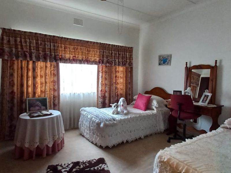 A bedroom featuring neutral walls, a large window with curtains, and classic ceiling detailing.
