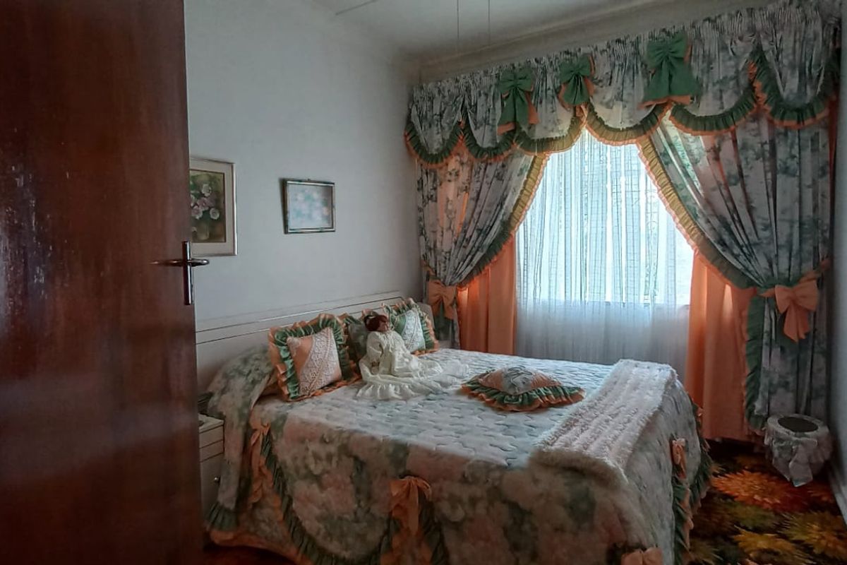 A bedroom featuring a built-in wardrobe and window treatments, currently styled with dated finishes and decor.
