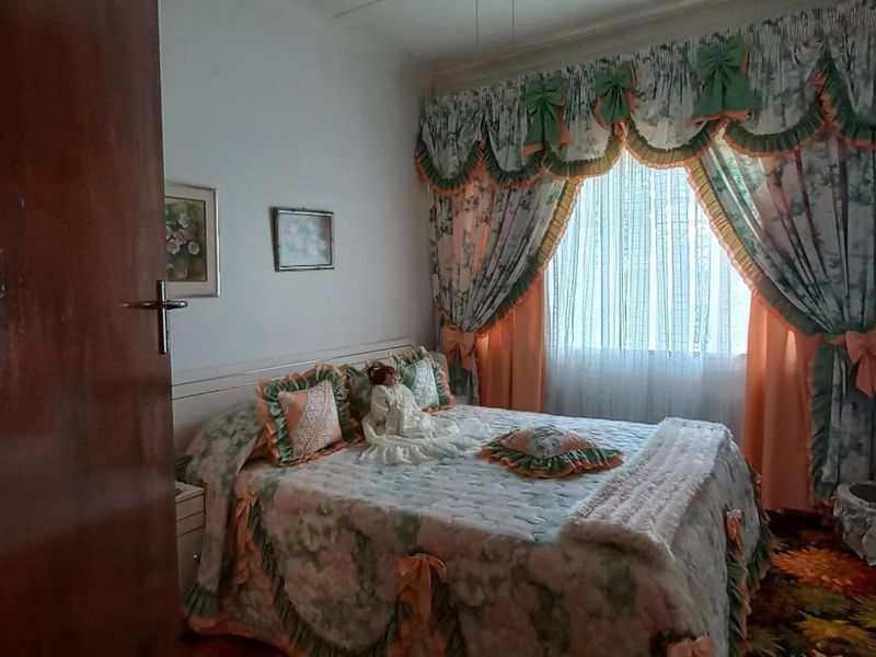 A bedroom featuring a built-in wardrobe and window treatments, currently styled with dated finishes and decor.
