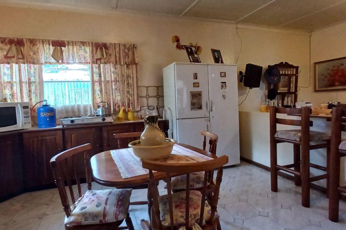 A functional kitchen featuring wooden cabinetry, tiled flooring, and a breakfast counter, offering a traditional layout with ample storage space.