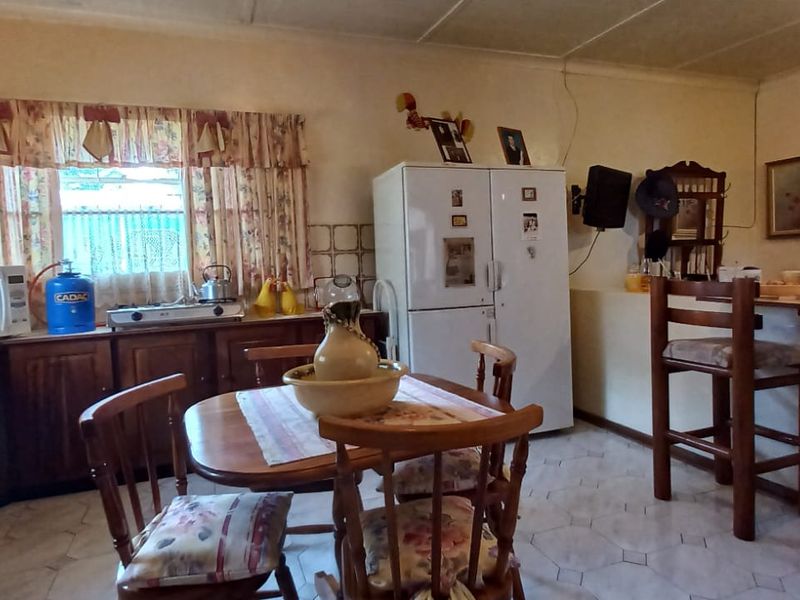 A functional kitchen featuring wooden cabinetry, tiled flooring, and a breakfast counter, offering a traditional layout with ample storage space.