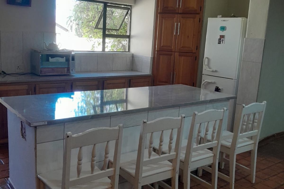 A functional kitchen featuring a central island with stone countertop, wooden cabinetry, and tiled flooring, offering a practical layout for daily use.