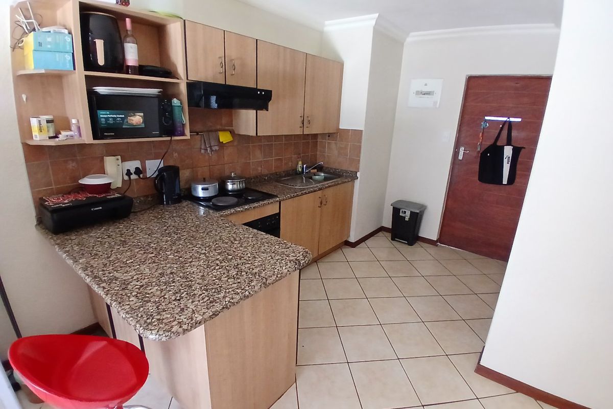 Compact kitchen featuring granite countertops, laminate cabinetry, built-in hob with extractor fan, and tiled flooring.