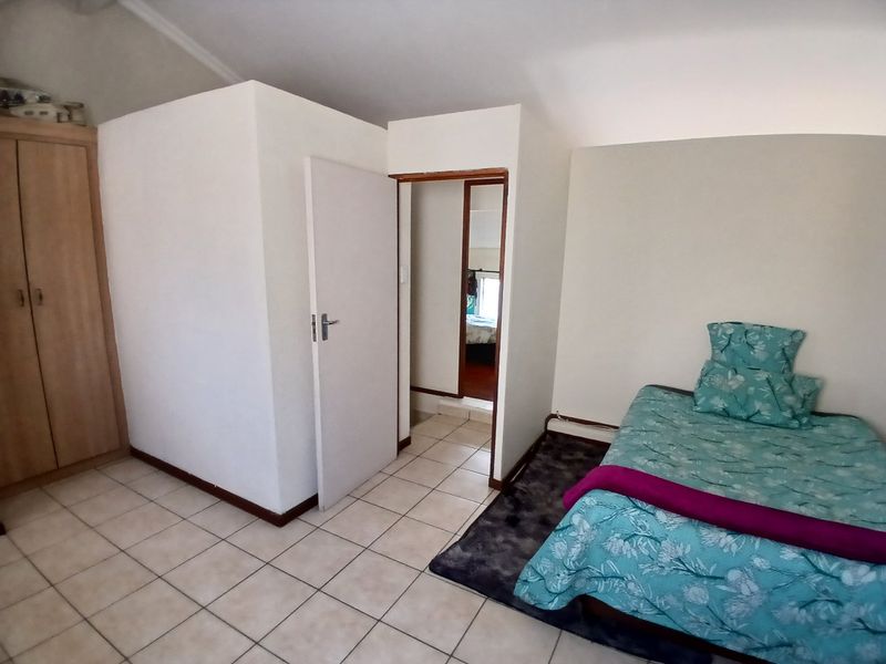 A bedroom featuring tiled flooring and a built-in wardrobe, with an adjacent doorway leading to another room.