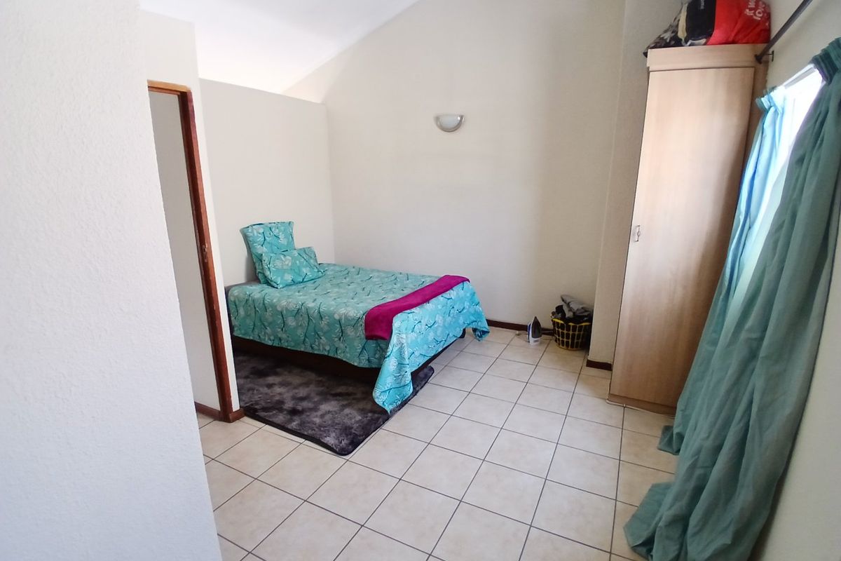 A bedroom featuring tiled flooring and a vaulted ceiling, providing a functional space with neutral wall finishes.