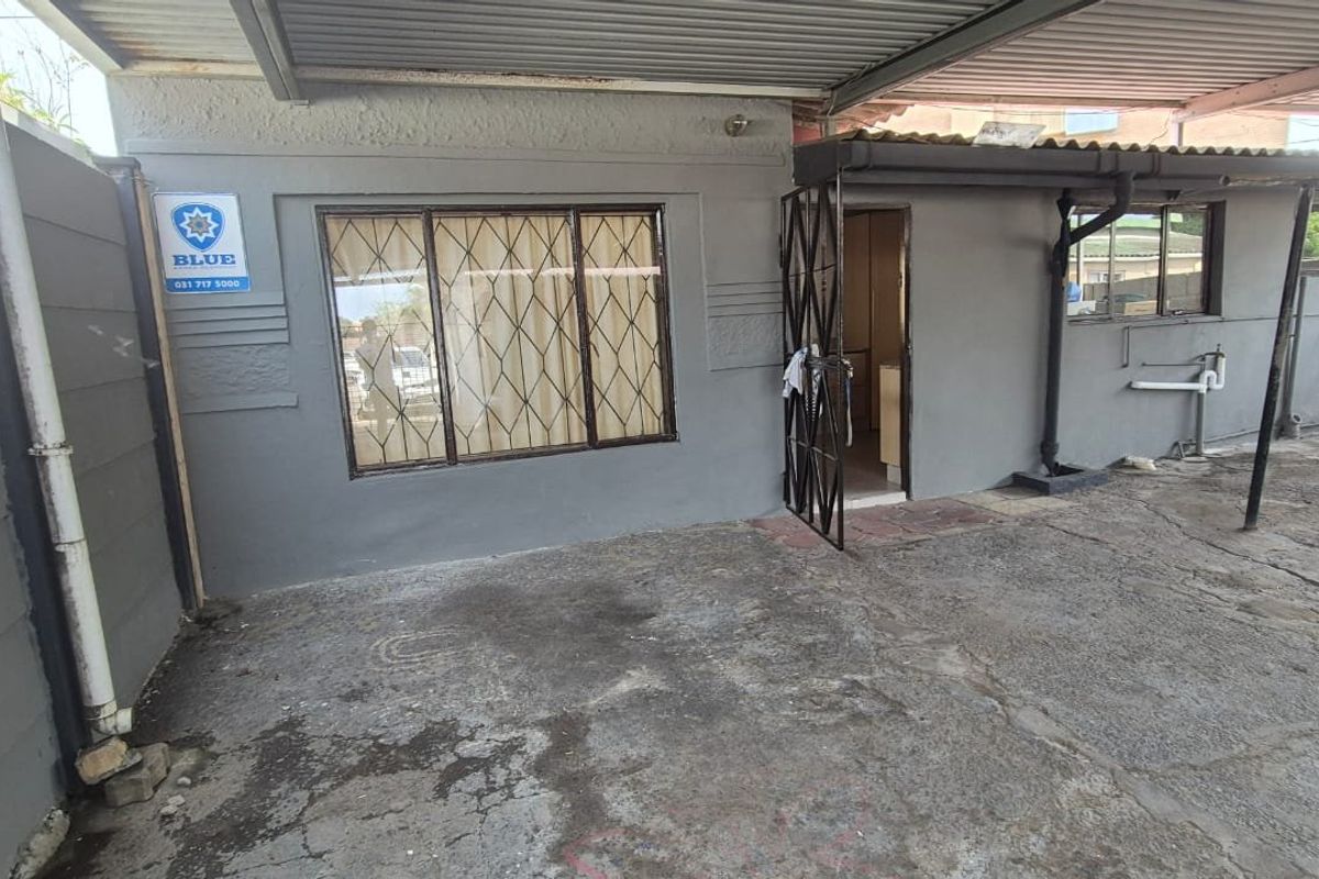 Rear exterior area featuring a covered patio space with concrete paving, security gate, and security bars on the window.