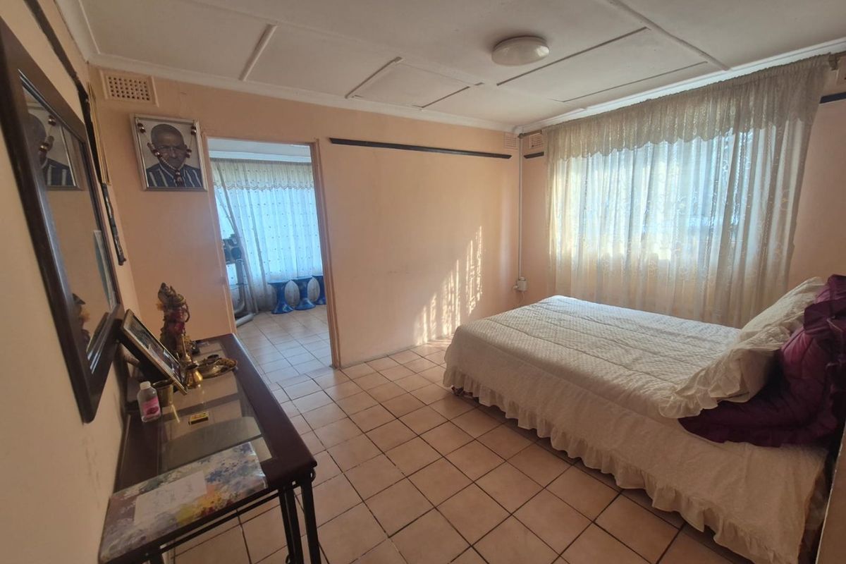 A bedroom featuring tiled flooring and a ceiling with panel tiles, offering a functional space with potential for cosmetic updates.