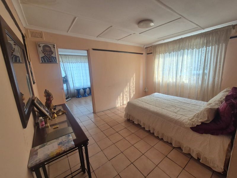 A bedroom featuring tiled flooring and a ceiling with panel tiles, offering a functional space with potential for cosmetic updates.