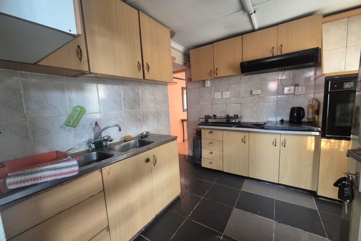A functional kitchen featuring built-in cabinetry, a double sink, integrated oven, and gas hob with tiled backsplash and flooring.