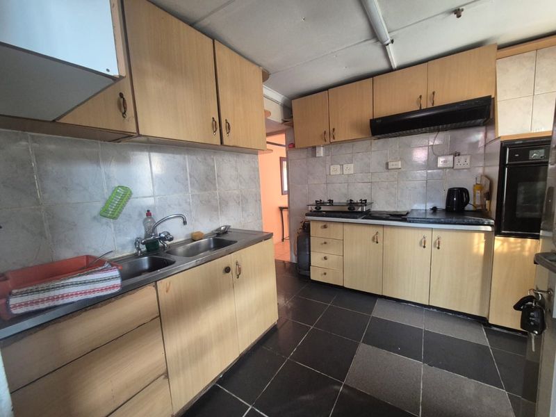 A functional kitchen featuring built-in cabinetry, a double sink, integrated oven, and gas hob with tiled backsplash and flooring.