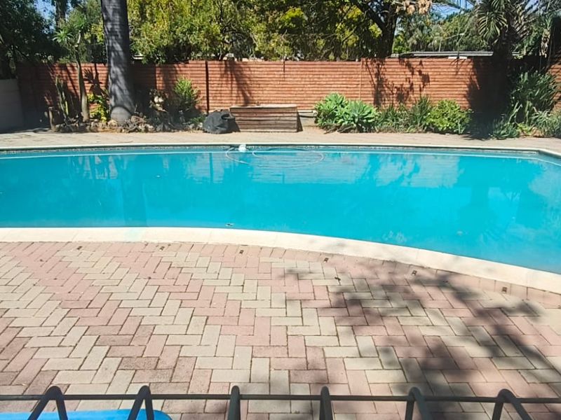 A private outdoor swimming pool area featuring brick paving surround and secure boundary walling.