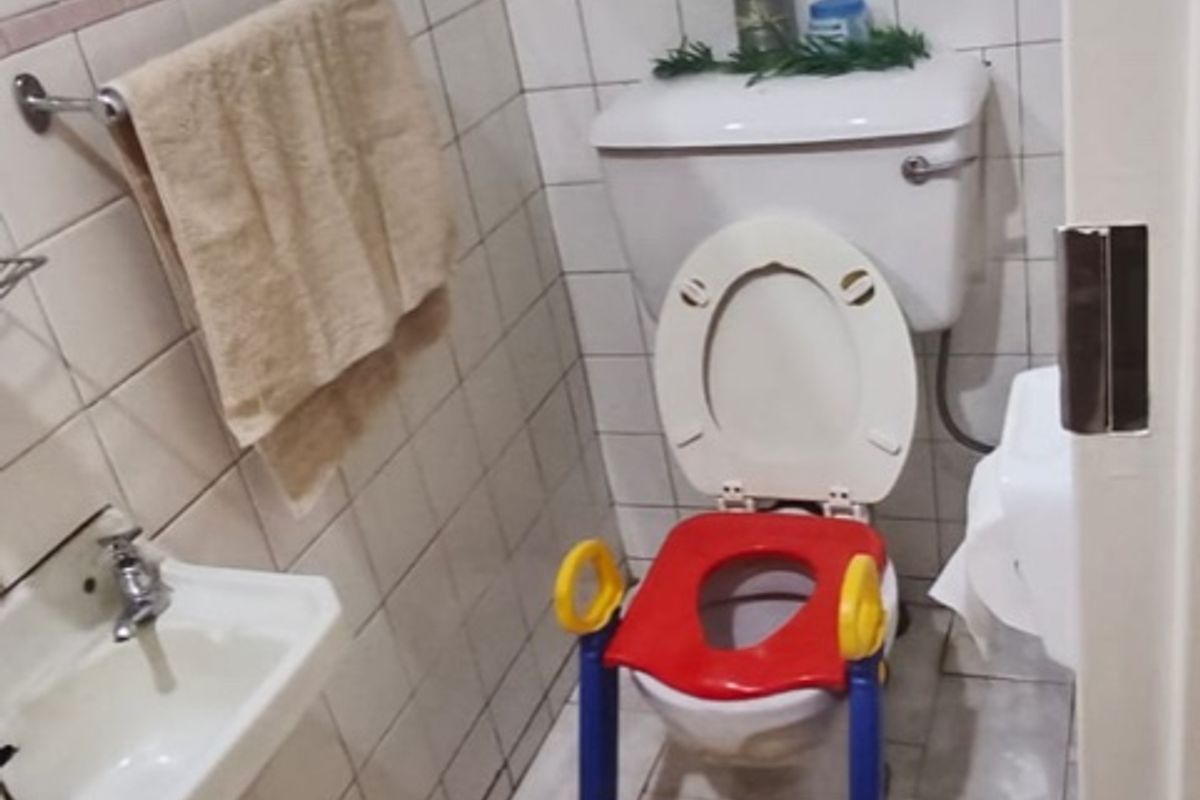A small guest bathroom featuring tiled walls and floors, a pedestal basin, and a standard toilet.
