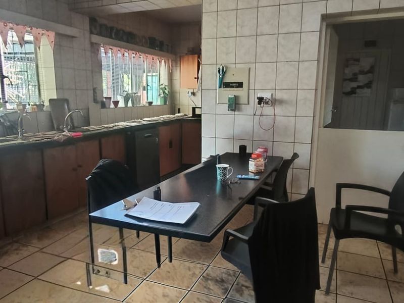 A dated kitchen featuring tiled walls and flooring, built-in cabinetry, and a double sink, offering significant potential for a modern renovation.