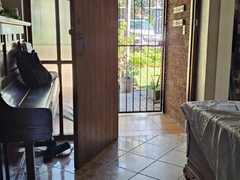 Entrance area featuring tiled flooring, a timber front door, and a security gate leading to the exterior.