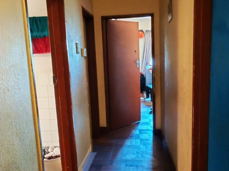 A narrow hallway featuring traditional parquet flooring and wooden door frames, providing access to adjacent rooms within the apartment.