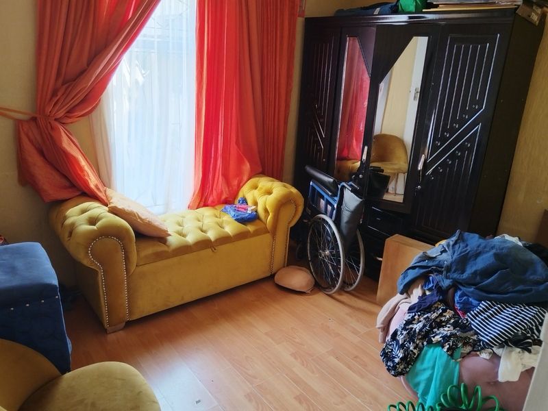 A bedroom featuring laminate flooring and a built-in wardrobe, offering a functional space with natural light from the window.