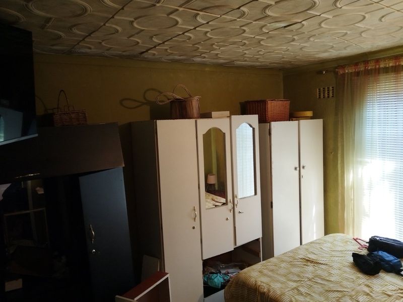 A bedroom featuring built-in wardrobes and a decorative patterned ceiling, offering potential for modernization and cosmetic updates.