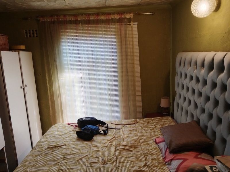 A bedroom featuring a window with blinds and a textured ceiling. The room requires cosmetic updates to improve its overall condition and appeal.