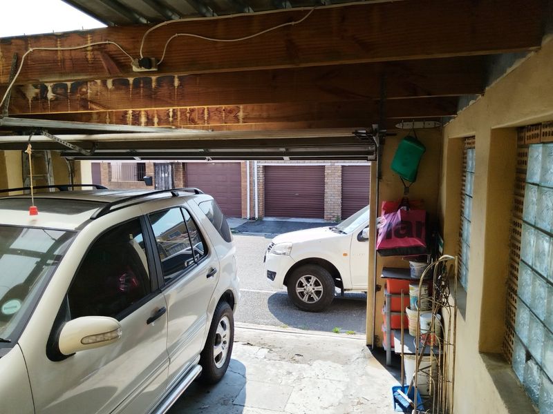 A functional garage space featuring exposed timber ceiling beams and a glass block window, providing secure parking and storage area.