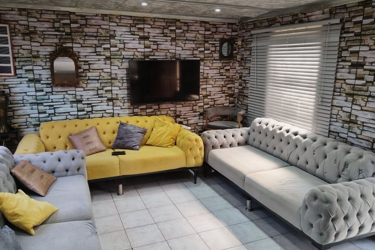Living room featuring tiled flooring, venetian blinds, and recessed ceiling lighting, with a prominent faux-brick wall finish.