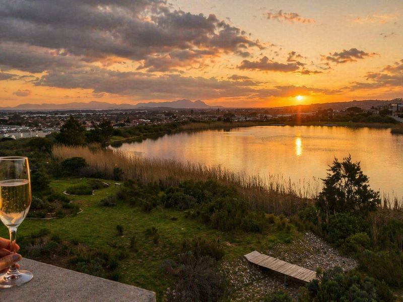 A scenic sunset view overlooking a tranquil lake and surrounding landscape, captured from an elevated vantage point.