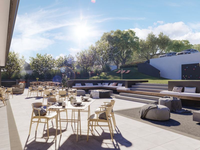 Expansive outdoor patio area featuring built-in concrete bench seating, a fire pit, and tiered landscaping with a climbing wall.
