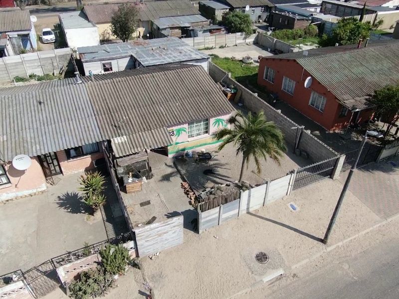 Aerial view of a residential property featuring a corrugated metal roof, enclosed yard with precast concrete boundary walls, and a gated entrance.