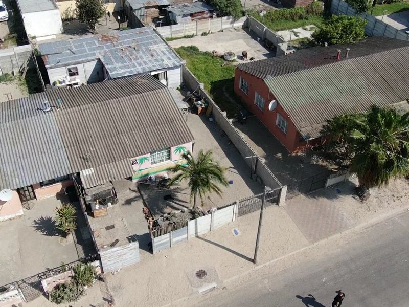 Aerial view of the property showing the residential building, corrugated roofing, boundary walls, and driveway access from the street.