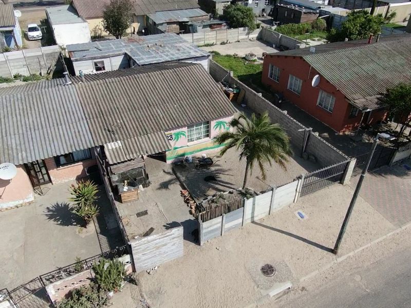 Aerial view of a residential property featuring a corrugated metal roof, enclosed yard with precast concrete boundary walls, and a gated entrance.