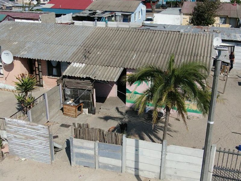 Aerial view of a residential property featuring a corrugated roof, precast concrete boundary walls, and an unpaved yard area.