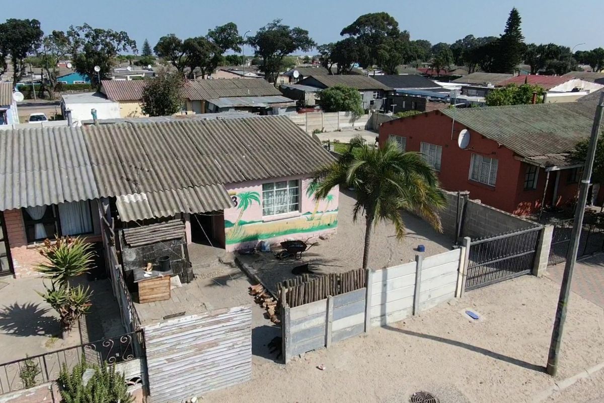 Aerial view of a residential property featuring a corrugated roof, enclosed yard with precast boundary walls, and a metal gate.