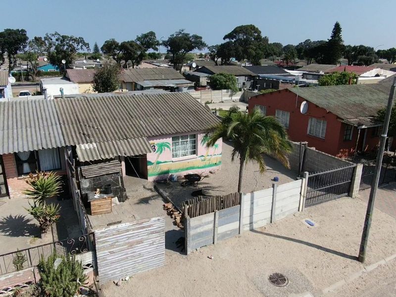 Aerial view of a residential property featuring a corrugated roof, enclosed yard with precast boundary walls, and a metal gate.