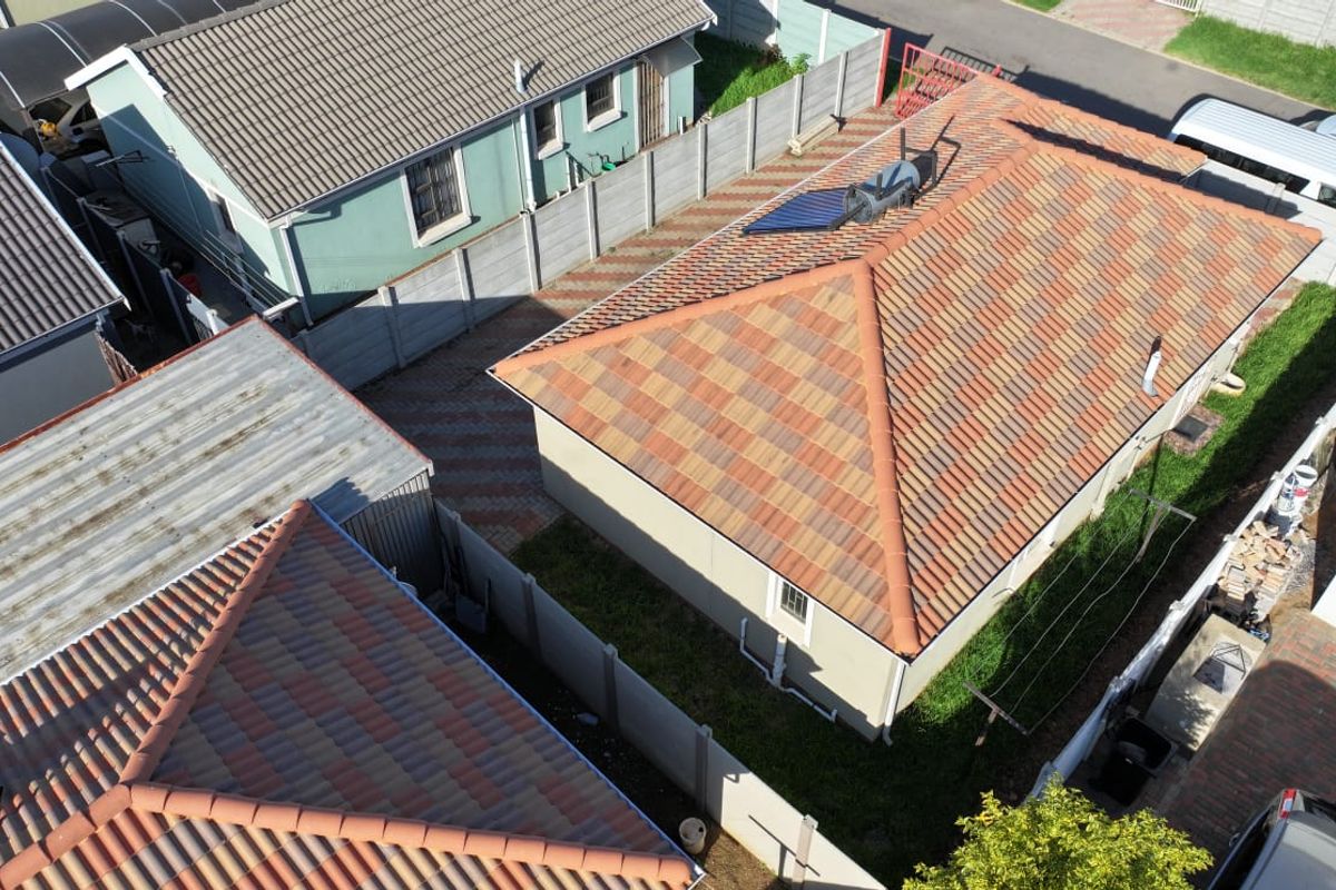Aerial view of the property showing the tiled roof, solar water heater, paved driveway, and surrounding precast concrete boundary walls.