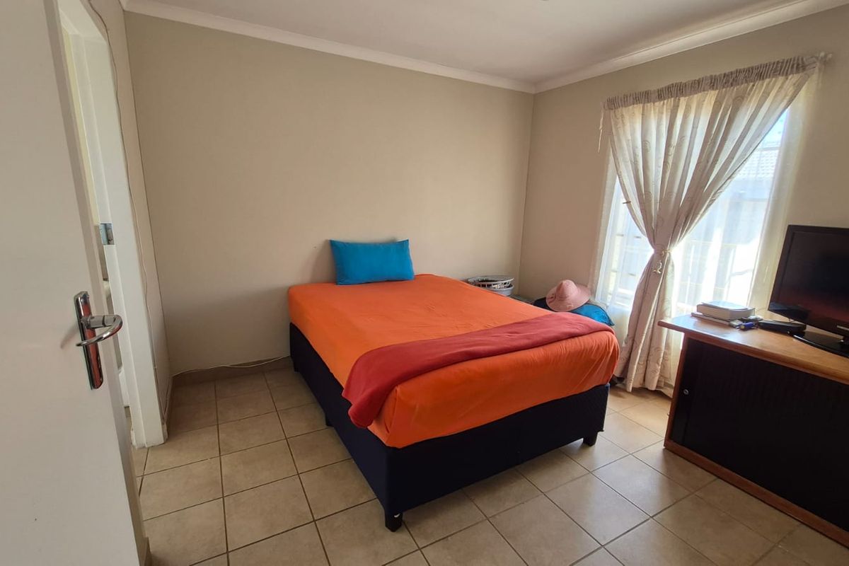 A functional bedroom featuring tiled flooring and a window with curtain rails, providing a neutral base for personalization.