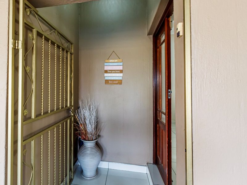 A functional entryway featuring a metal security gate, a wooden door, and tiled flooring, providing a secure and clean transition into the home.