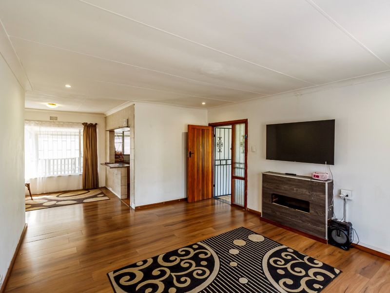 Open plan living area featuring laminate flooring, recessed lighting, and a convenient pass-through window connecting to the kitchen space.