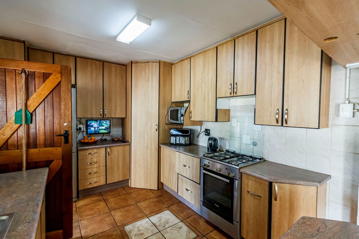Functional kitchen featuring light wood-look laminate cabinetry, tiled flooring, a gas stove with oven, and ample built-in storage space.
