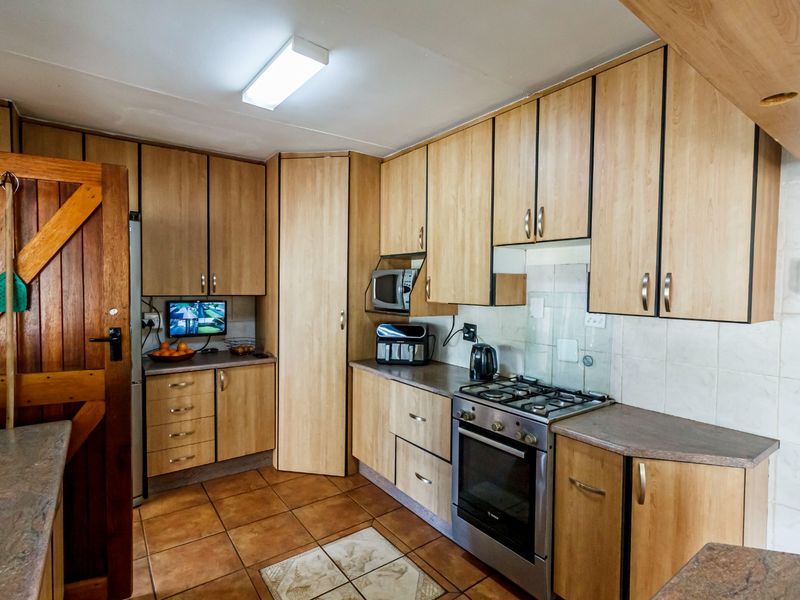 Functional kitchen featuring light wood-look laminate cabinetry, tiled flooring, a gas stove with oven, and ample built-in storage space.