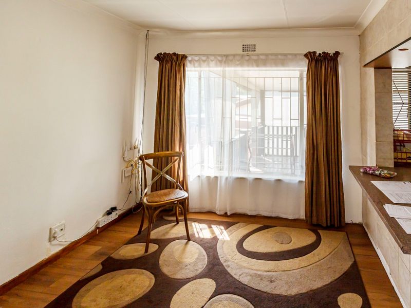 Open plan living area featuring wooden flooring, a built-in breakfast bar, and large windows with security bars.