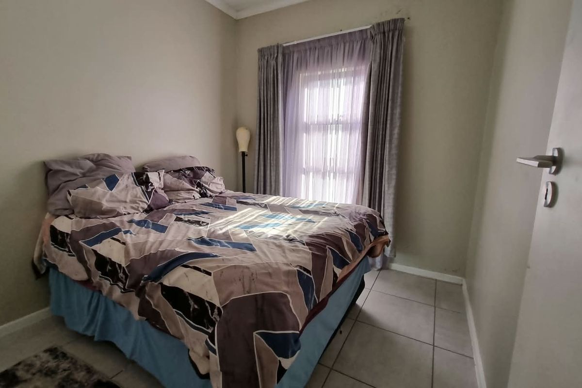 A compact bedroom featuring tiled flooring and a window with curtain tracks, providing a functional space for rest.