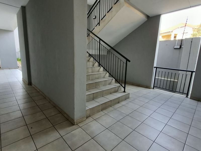 A clean, tiled apartment hallway featuring a staircase with metal railings and access to unit 206.