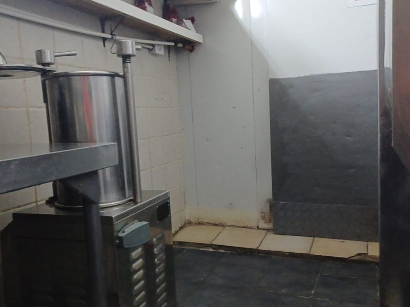 A utilitarian scullery or prep area featuring tiled surfaces and wall-mounted shelving, currently showing signs of wear and requiring maintenance.