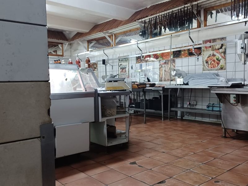 A commercial-style kitchen or butchery area featuring tiled surfaces, stainless steel prep stations, and industrial food processing equipment.