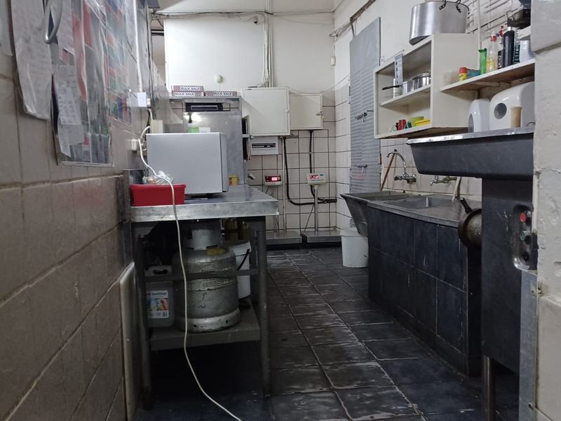 A functional industrial-style scullery or prep area featuring tiled surfaces, stainless steel work stations, and a deep basin sink.
